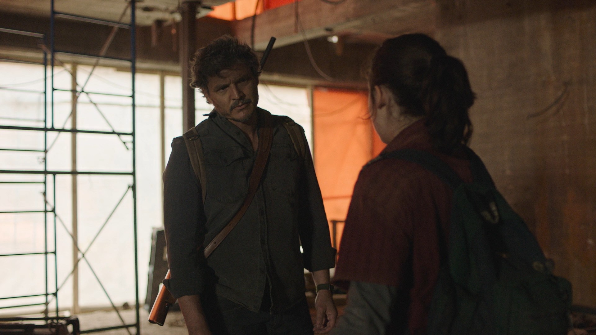 Joel confronts Ellie inside a half-finished building, tension rising amid scaffolding and shadows in HBO’s The Last of Us.