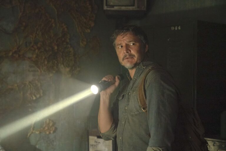 Pedro Pascal as Joel explores a dark, infected building with a flashlight in HBO’s The Last of Us Episode 1.